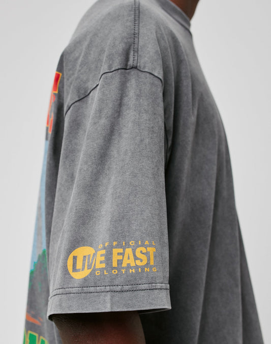 A person wears the LIVE FAST DIE YOUNG LFDY Metro Boomin Tee in oversized faded grey 100% cotton with a yellow Official Live Fast Clothing print on the sleeve, shown from the side against a plain background.