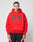 A person faces the camera in an oversized bright red Live Fast College Hooded by LIVE FAST DIE YOUNG, featuring bold black LIVE FAST text and black/red athletic shorts, made from a comfortable polyester blend, against a plain white background.