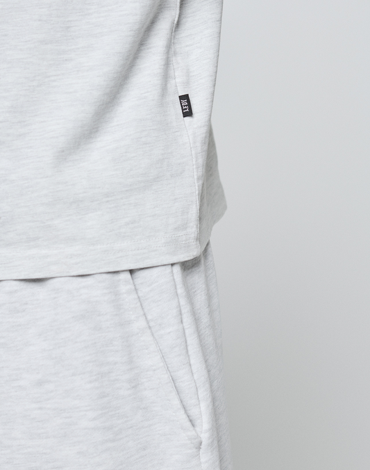 Close-up of a person wearing LIVE FAST DIE YOUNG’s Basic Chest Tee in light gray 100% Baumwolle. The regular fit tee features a soft texture and a small black tag sewn to the hem on the left side.