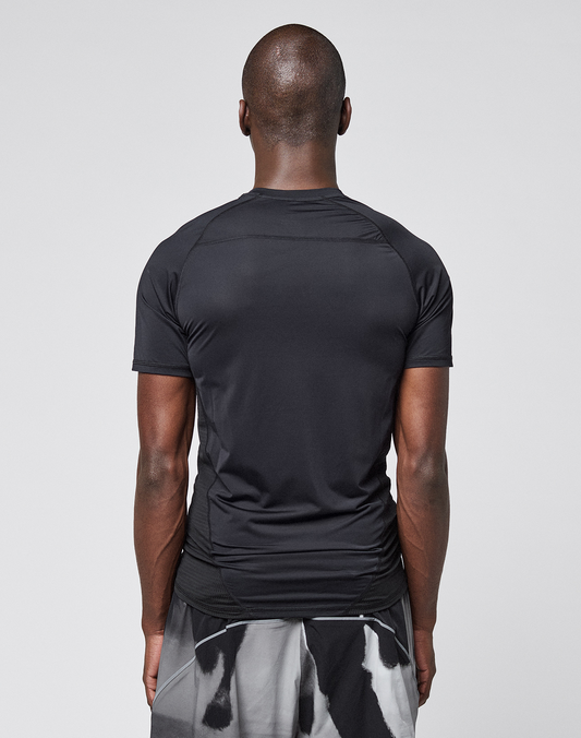 A person with short hair, seen from behind, wears the LFDY Performance Slim Tee by LIVE FAST DIE YOUNG and black-and-white patterned shorts against a plain light gray background.