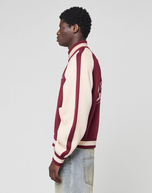 A person stands in profile wearing the LIVE FAST DIE YOUNG Boxy Knit Zip Jacket with an oversize fit and light blue jeans against a plain light gray background.