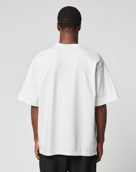 A person stands with their back to the camera, wearing the LIVE FAST DIE YOUNG Fuck Die Young Tee—a plain white 100% Baumwolle short-sleeve t-shirt—and black pants against a neutral light background.
