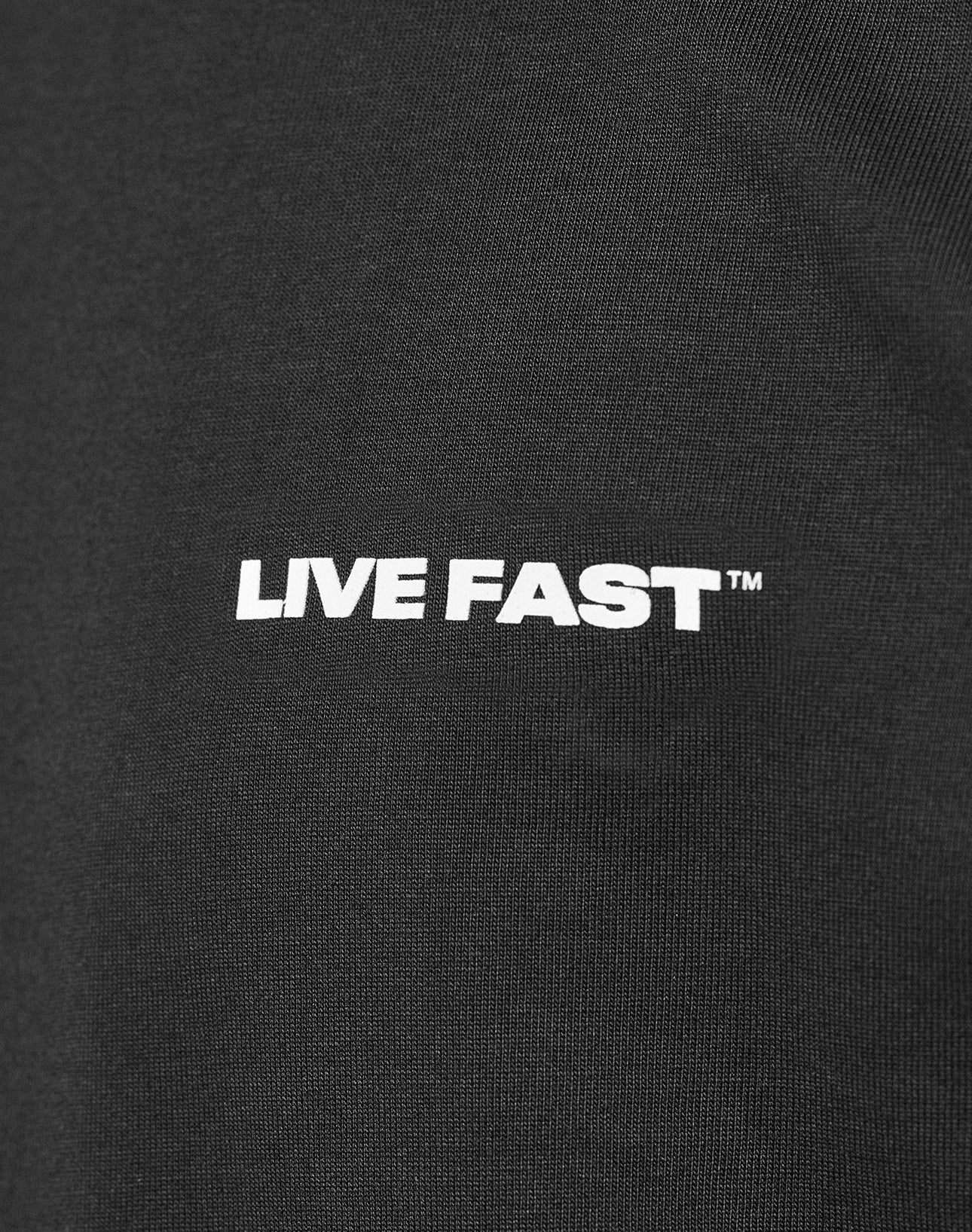 Close-up of the Live Fast Plain Tee by LIVE FAST DIE YOUNG, a black Regular Fit made from 100% cotton, featuring a bold white LIVE FAST™ front print.