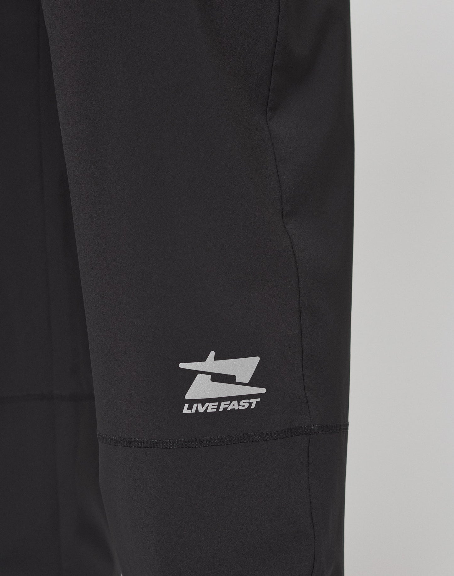LIVE FAST DIE YOUNG's Live Fast Performance Running Pants feature an oversized fit, elastic waistband, and cuffed ankles, shown on a plain light gray background.