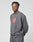 A person in a loose, dark gray LIVE FAST DIE YOUNG DY Sweater aus Baumwolle mit Oversize Fit und Raglan-Ärmeln steht vor einem schlichten hellen Hintergrund. Das Sweatshirt trägt ein rot-weißes Grafiklogo auf der Brust.