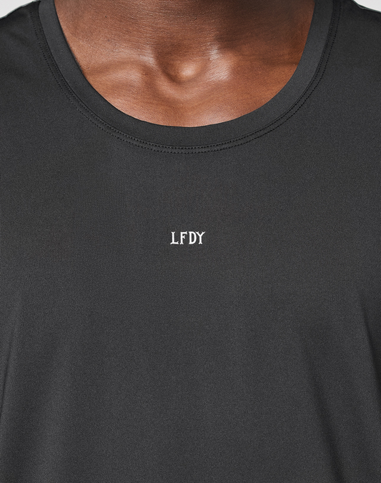 Close-up of a person wearing the LFDY Performance Tank by LIVE FAST DIE YOUNG, featuring a reflective white "LFDY" logo at the center chest. The regular fit highlights the neck and upper chest.