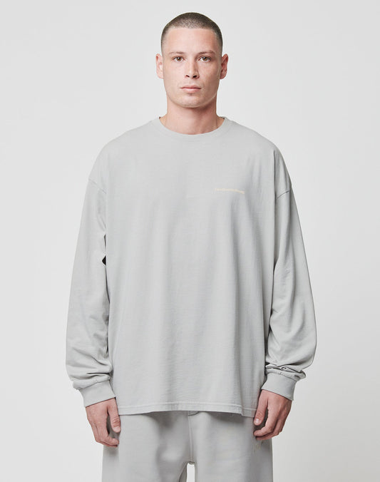 A person with short hair stands against a plain background wearing the LIVE FAST DIE YOUNG Basic Longsleeve and matching pants in light grey, both made from 100% Baumwolle, with a neutral expression and arms by their sides.