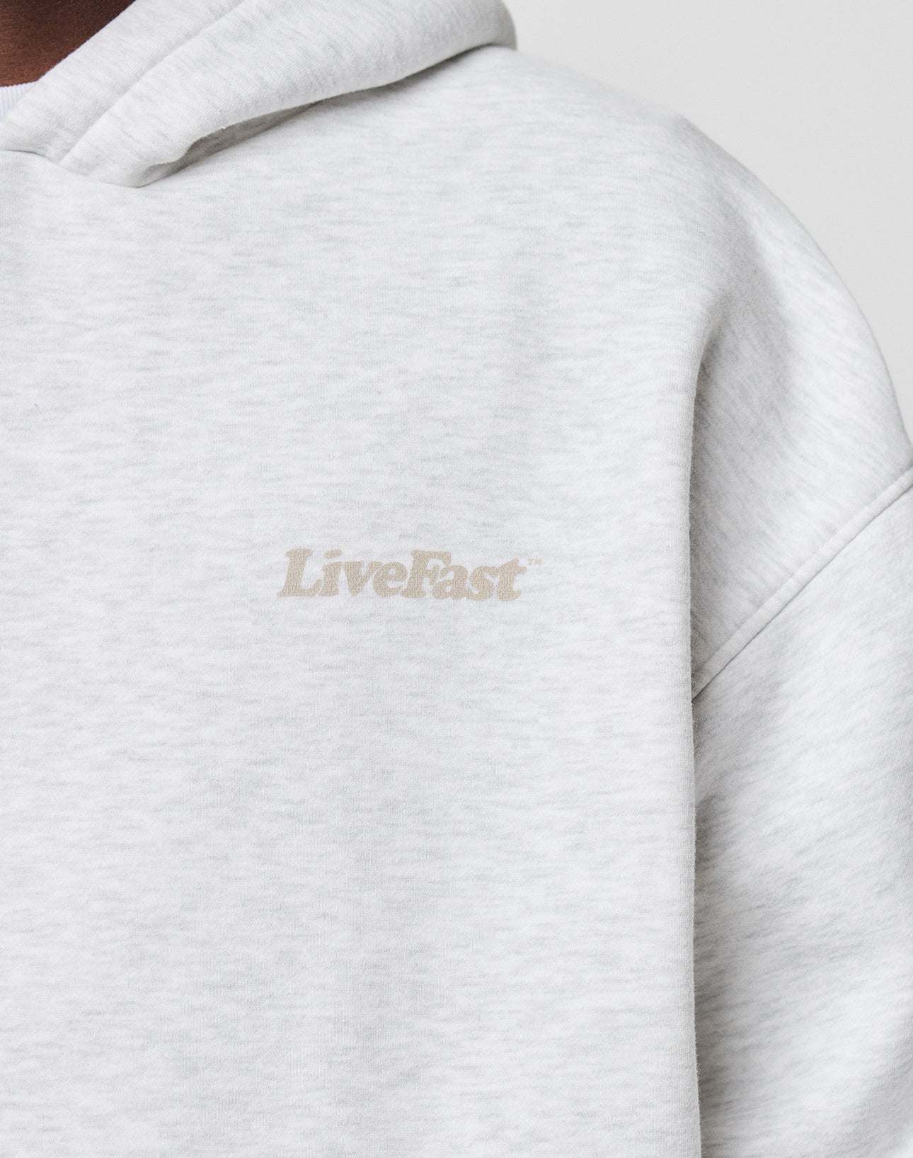 Close-up of the light gray Basic 360 Hooded by LIVE FAST DIE YOUNG in Oversize Fit, featuring LiveFast printed in small, subtle, light-colored letters on the left chest.