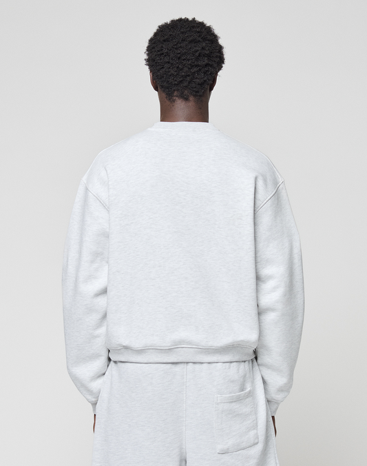 A person is seen from behind wearing the LIVE FAST DIE YOUNG Basic +49 Chest Sweater in an oversize fit, light gray shade, paired with matching shorts, standing against a plain light background.