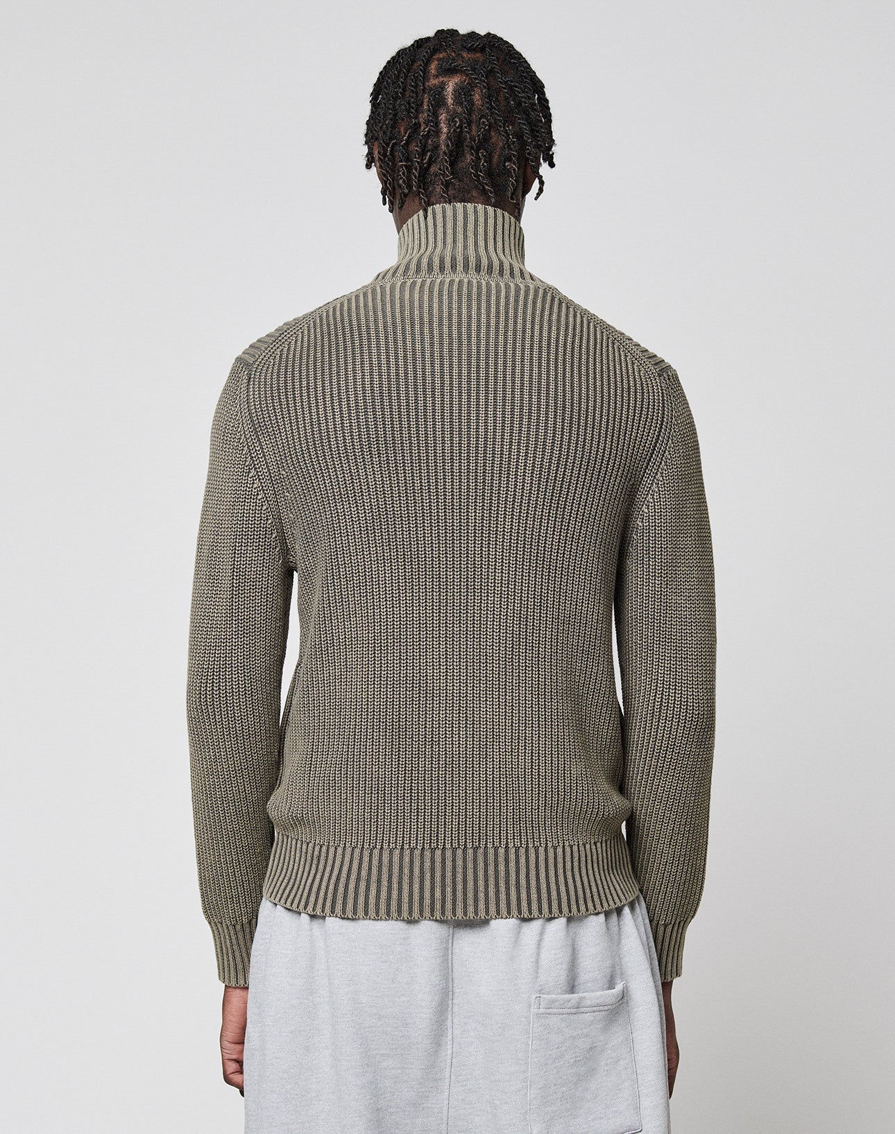 A person with short, twisted hair is seen from behind wearing the LIVE FAST DIE YOUNG LFDY Knit Jacket in olive green and light gray pants with an exposed back pocket, standing against a plain light background.