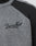 Close-up of the Boxy Knit Zip Jacket by LIVE FAST DIE YOUNG, in gray with black raglan sleeves and collar, featuring "Live Fast" embroidered in black cursive on the chest.