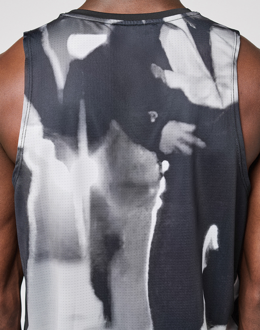 A close-up shows a person in the LFDY Performance Tank by LIVE FAST DIE YOUNG, made from light fabric with a black and white graphic print on the back. The Regular Fit highlights their arms and shoulders.