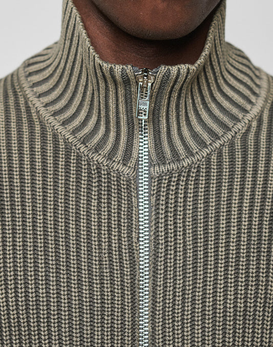 Close-up of a person wearing the LFDY Knit Jacket by LIVE FAST DIE YOUNG, featuring ribbed texture, high collar, and zip-up design in gray and beige shades. Zipper is partially closed; only the lower half of the face is visible.