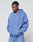A man stands with his hands in the pockets of a blue LIVE FAST DIE YOUNG Basic Hooded Zip and matching sweatpants, featuring a subtle faded look, looking down with a neutral expression against a plain light background.