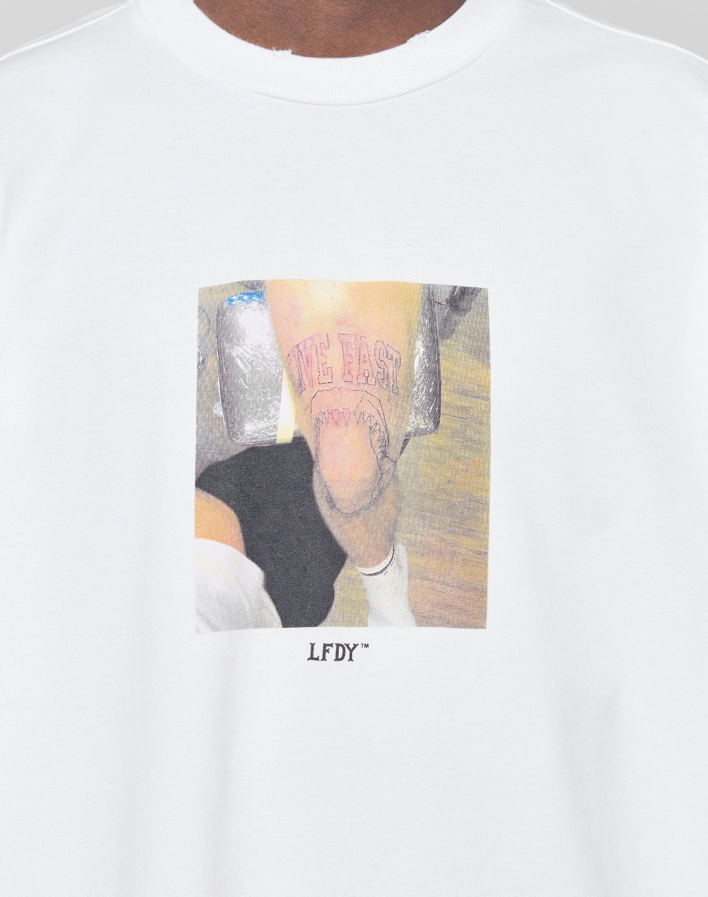 The LFDY Sharkhunter Tee by LIVE FAST DIE YOUNG is an oversized white T-shirt with a printed tattooed leg photo, LIVE FAST text, red design, and LFDY™ below. Made from 100% Baumwolle for comfort.