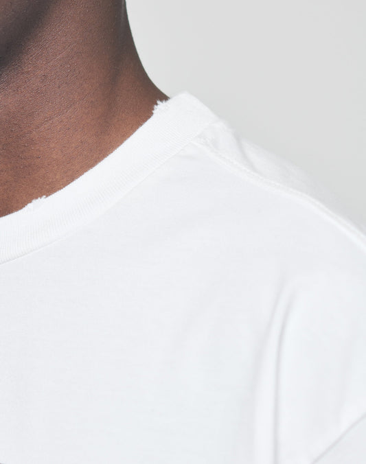 Close-up of a person wearing the oversized LFDY Sharkhunter Tee by LIVE FAST DIE YOUNG in white 100% Baumwolle, with a raw, distressed neckline. Neck, shoulder, and upper chest are visible against a light gray background.