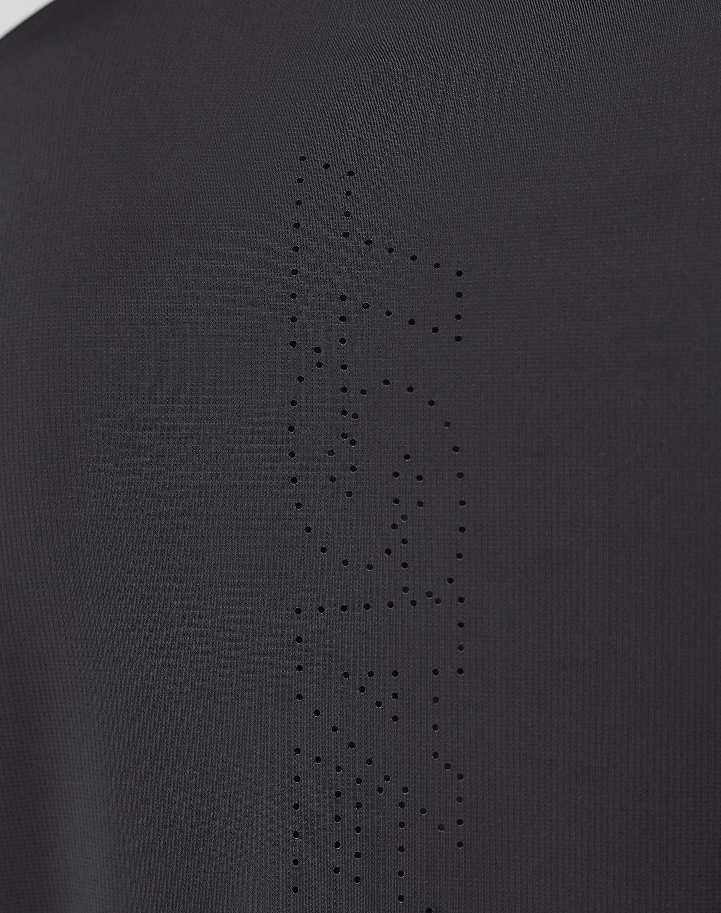 Close-up of the Live Fast Performance Longsleeve by LIVE FAST DIE YOUNG, showing black fabric with a mesh insert and perforated holes forming FAST vertically, highlighting the garment’s texture and fine details.