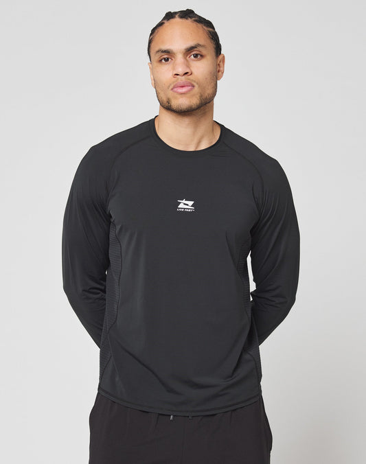 A person with braided hair wears the LIVE FAST DIE YOUNG Live Fast Performance Longsleeve, a black slim fit athletic shirt with a mesh insert and small white logo on the chest, standing before a plain light gray background.