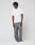 A person with short, textured hair stands against a plain background, wearing the LIVE FAST DIE YOUNG Live Fast Plain Tee, loose gray pants, and white sneakers. They have a relaxed posture and a neutral expression.