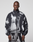 A person wearing a loose-fitting, black and white LFDY Performance Jacket by LIVE FAST DIE YOUNG with a zip-up high collar and matching pants featuring a reflective logo print stands facing forward against a plain light background.