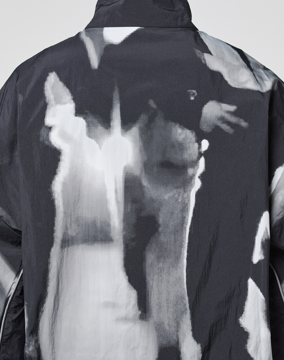The LFDY Performance Jacket by LIVE FAST DIE YOUNG features a black-and-white abstract nylon pattern with blurred shapes, a reflective logo print on the back, and delivers a modern edge.