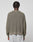 A person with short, twisted hair is seen from the back wearing the LIVE FAST DIE YOUNG LFDY Knit Sweater in an oversize olive-green ribbed design with dropped shoulders, paired with light gray pants against a plain background.