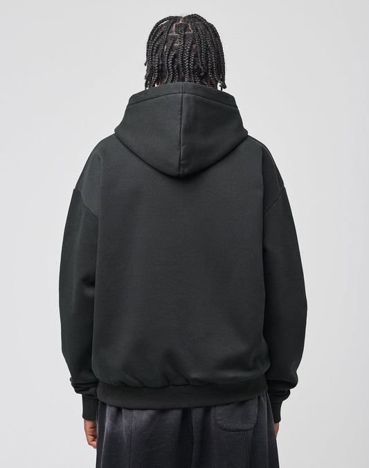 A person with braided hair, seen from behind, wears the LIVE FAST DIE YOUNG Live Fast Axe Hooded in oversize fit and dark pants, standing against a plain light gray background.