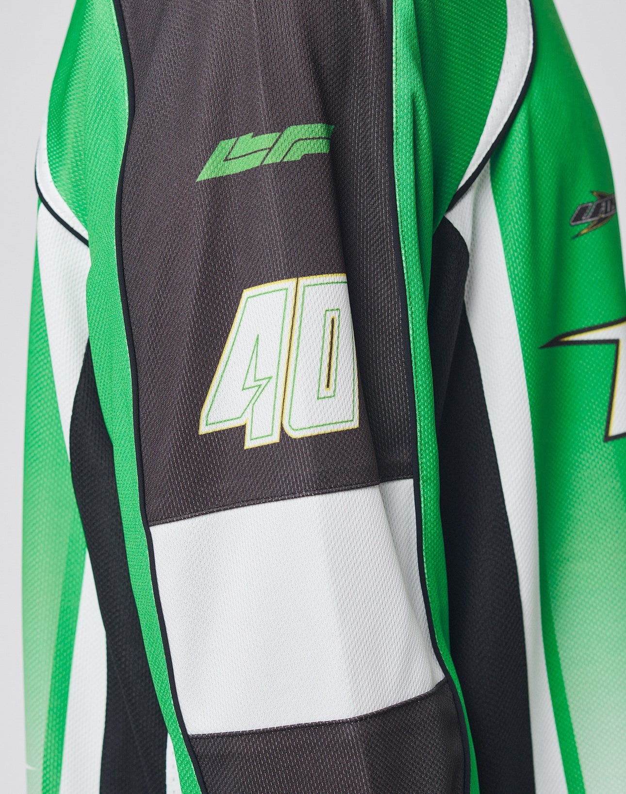 A close-up of the LIVE FAST DIE YOUNG LFDY Motorcross Jersey in an oversize fit, showcasing green, black, and white colors, bold multi-logo prints on the front and sleeve, and featuring the number 40.