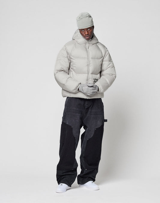 A person wearing the LIVE FAST DIE YOUNG Live Fast Puffer Jacket in light gray, with matching beanie and gloves, loose black pants, and white sneakers stands against a plain white background.