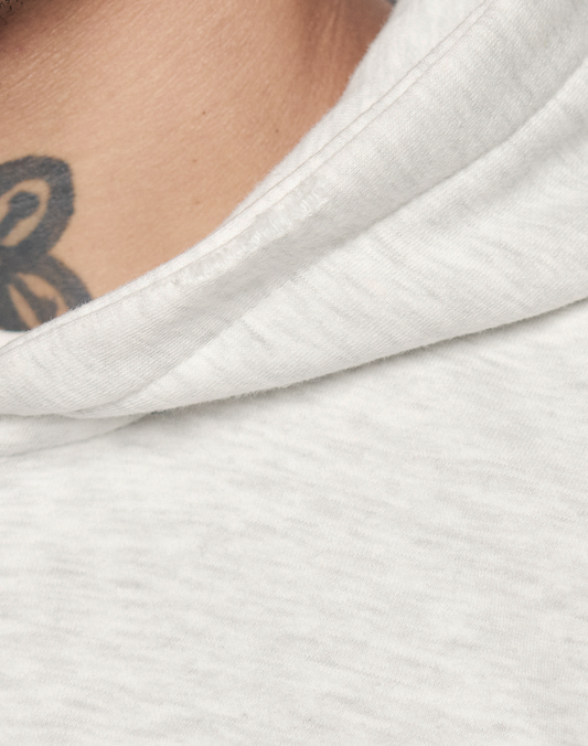 Close-up of a person in the LIVE FAST DIE YOUNG Basic Hooded Zip, Oversize Fit, light gray color, showing fabric texture, a glimpse of their neck, and part of a black tattoo.