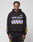A person in an oversize fit black LFDY Racing Hooded by LIVE FAST DIE YOUNG, featuring glossy white and lavender LIVE FAST Everything print with yellow and lavender stripes, plus matching black pants, stands against a light gray background.