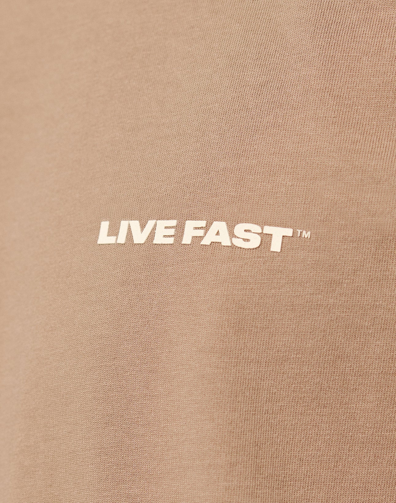 Close-up of the Live Fast Plain Tee by LIVE FAST DIE YOUNG, made from 100% brown cotton, featuring the text LIVE FAST™ as a bold white front print in capital letters.