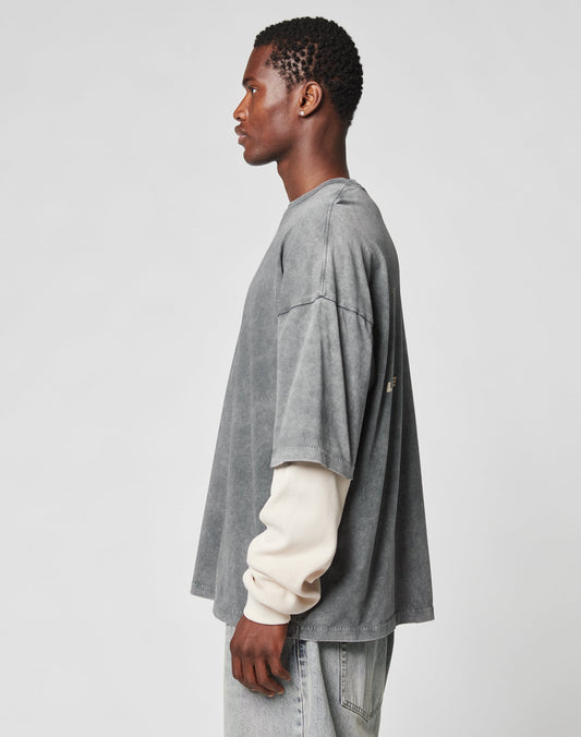 A man stands in profile against a plain background, wearing the LIVE FAST DIE YOUNG LFDY Double Layered Longsleeve with an oversize fit, paired with light-wash jeans.