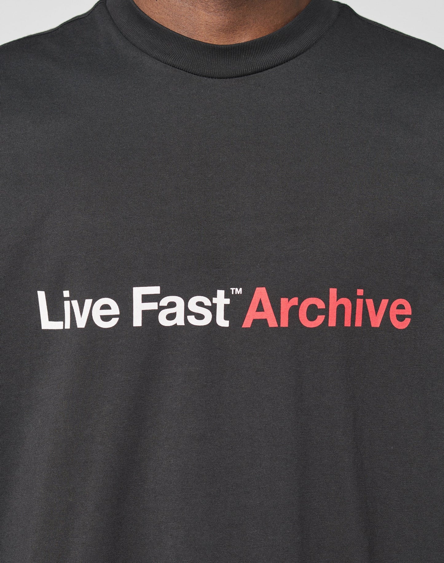 Close-up of the Live Fast Archive Tee by LIVE FAST DIE YOUNG, a black cotton t-shirt with bold Live Fast in white and Archive in red on the front, designed in an oversized fit for a modern style.
