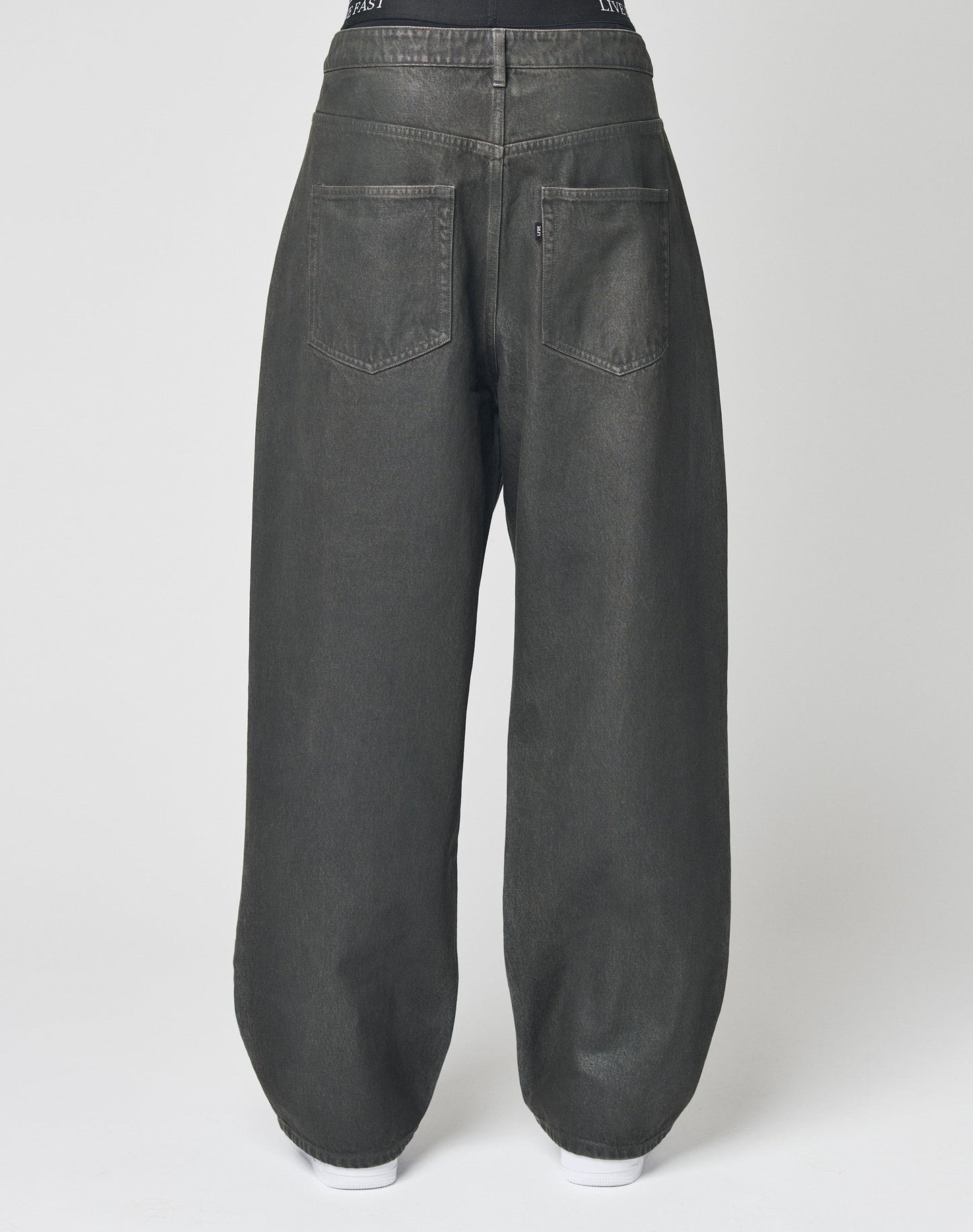 Back view of the LFDY Coated Baggy Denim by LIVE FAST DIE YOUNG—high-waisted, loose-fitting black jeans with a straight leg and large square back pockets, shown against a plain white background.