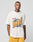 A tattooed man wears the LIVE FAST DIE YOUNG LFDY Adults Only Tee in white with bold lettering and yellow basketball shorts, standing against a plain light gray background.