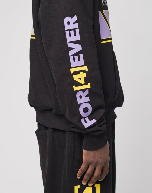 A person wears the LFDY Racing Hooded set by LIVE FAST DIE YOUNG—an oversized black sweatshirt and pants with glossy purple and yellow FOR [4]EVER text on the sleeve and a yellow [4] graphic on the pants, made from soft Baumwolle Polyester.