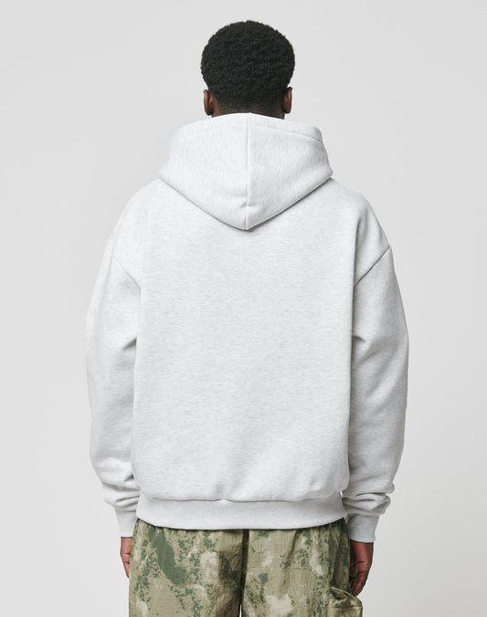 A person wears an oversized Live Fast Box Hooded light gray hoodie from LIVE FAST DIE YOUNG and green camo pants, standing with their back to the camera against a plain, light background.