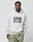 A man wears the LIVE FAST DIE YOUNG Live Fast Box Hooded in light gray with bold puffer print text and camouflage pants, standing against a plain background and looking at the camera. Made from hochwertiger Baumwolle.