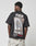 Wearing the LIVE FAST DIE YOUNG LFDY F*ck Phones Tee—an oversized black cotton T-shirt featuring bold white and red FUCK PHONES Live Fast Archive text and a back graphic—someone stands against a plain background.