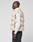 A man stands in profile against a plain background, wearing the LIVE FAST DIE YOUNG Live Fast Puffer Vest in oversize light beige with transparent outer fabric, over a light gray long-sleeve shirt and dark pants.