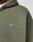 Close-up of a person wearing the olive green LIVE FAST DIE YOUNG Basic Hooded Zip, featuring white LFDY™ embroidery on the chest and a subtly faded fabric for a casual, worn-in look.