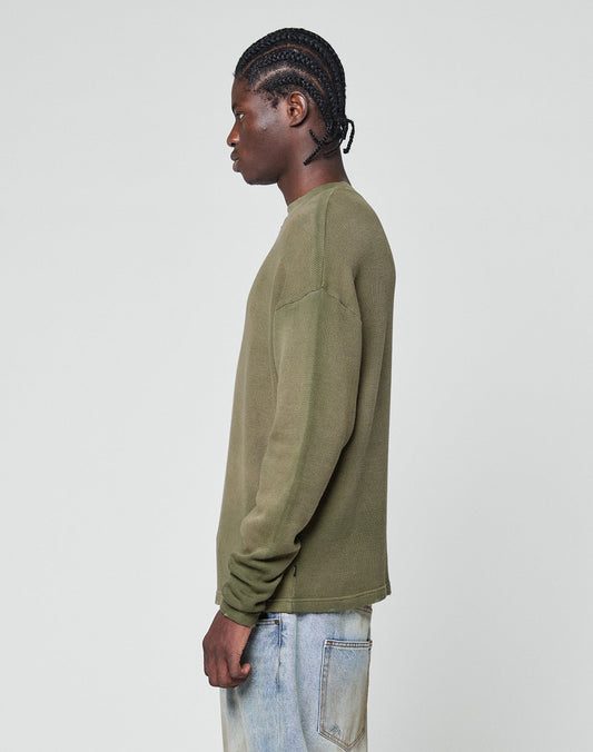 A person with braided hair stands in profile against a plain light background, wearing the LIVE FAST DIE YOUNG LFDY Rib Knit Longsleeve in olive green and light blue jeans with individuellem Wasch-Effekt and visible back pocket stitching.