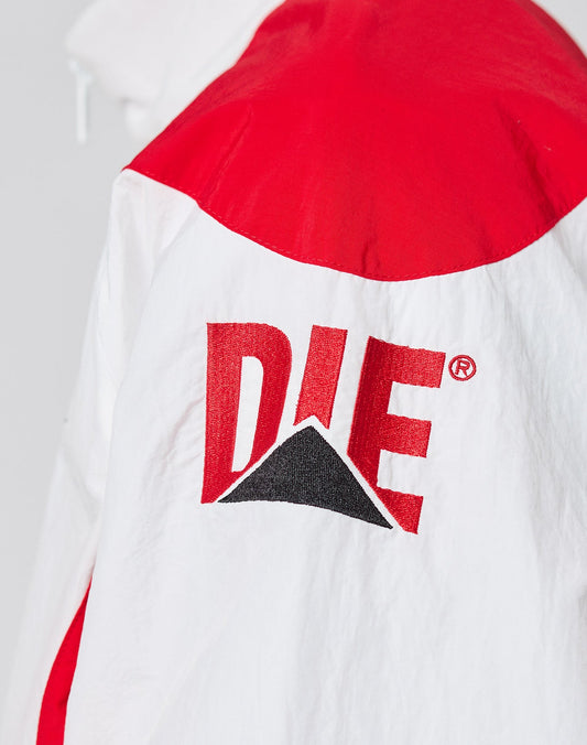 A close-up of the LFDY Trackjacket 3000 by LIVE FAST DIE YOUNG shows a white jacket with red shoulder panel and bold red DIE text above a black triangle on the back. Regular Fit with Branded Reißverschluss-Puller adds stylish detail.