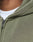 Close-up of a person wearing the LIVE FAST DIE YOUNG Basic Hooded Zip in olive green, featuring a faded look, visible zipper and fabric texture, and distressed collar stitching over a white shirt.