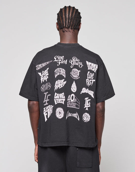 A person with braided hair is seen from behind wearing the LFDY Logo Tee by LIVE FAST DIE YOUNG, a black Oversize Fit T-shirt featuring bold white graphics and phrases like "Live Fast Die Young" on the back. | model