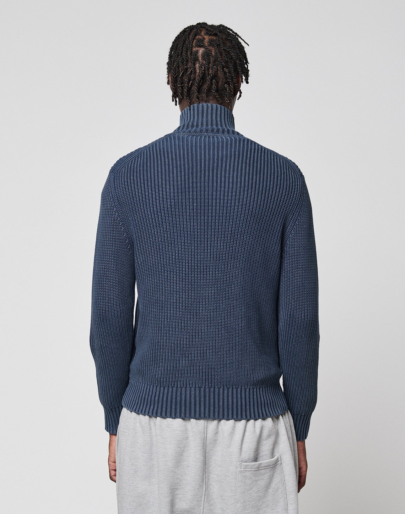 A person with short, twisted hair is seen from behind wearing the LIVE FAST DIE YOUNG LFDY Knit Jacket in blue and light gray pants against a plain light background.