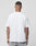 A person with tattooed arms and neck stands with their back to the camera, wearing a LIVE FAST DIE YOUNG LFDY Blank Tee in plain white (100% Baumwolle) and light gray pants against a plain, light gray background.