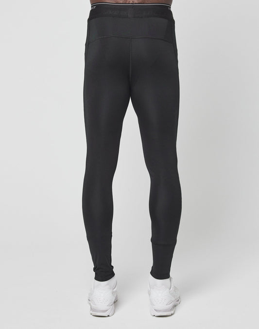 A person wearing LIVE FAST DIE YOUNGs Live Fast Performance Tights in slim fit black with an elastic waistband and white sneakers, shown from the back against a plain white background.