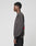 A young man stands in profile against a plain light background, wearing the LIVE FAST DIE YOUNG LFDY F*ck Sweater—an oversize fit dark gray Baumwolle sweatshirt with a graphic back design—and black pants.
